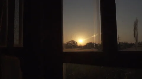 Slow motion of a sunrise through an old window hidden in the middle of nature. Stock Footage 297577656