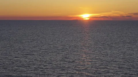 Slow Motion Sunset with Distant Vessel and Deep Colors Over Flat Ocean Surface Stock Footage 309420188