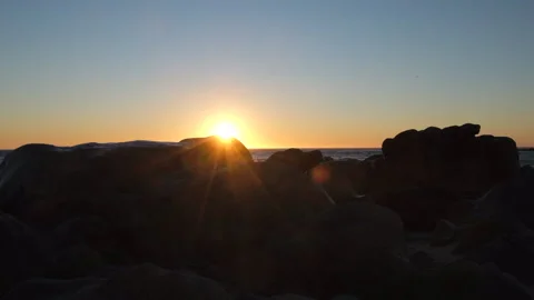 Slow motion sunset reveal on beach from behind rocks. Stock Footage 161246207