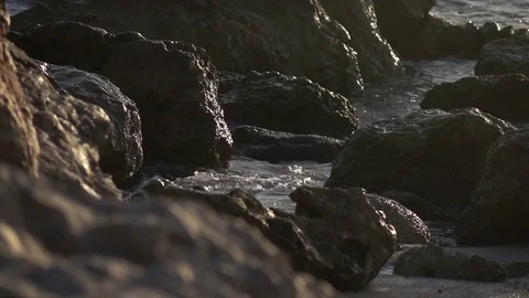 Slow Motion Surf Washing Up Between Boulders on Beach Stock Footage 78211207