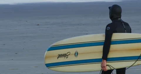 Slow motion of a surfer approaching the water at Morro Bay, Claifornia Stock Footage 99143923