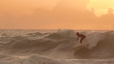 SLOW MOTION: Surfer rides a big wave and crashes into ocean on a summer evening. Stock Footage 84310268