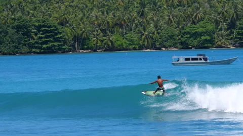 SLOW MOTION: Surfer riding a glassy turquoise wave with surf taxi in background Stock Footage 336755968