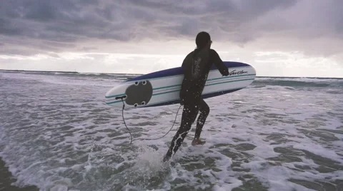 Slow motion surfer running in ocean in San Diego Stock Footage 64670339