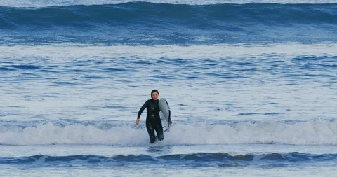 Slow motion of a surfer walking in Morro Bay, Claifornia Stock Footage 99143458