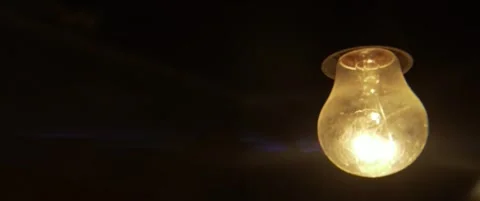 Slow motion swinging ancient light bulb anamorphic 5.7k video Stock Footage 304576145
