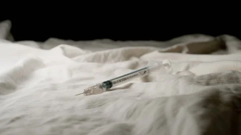 SLOW MOTION: Syringe falls on a bed Vídeos de archivo 202065749