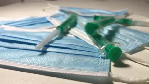 Slow motion of syringes fall onto a medical mask on the table Stock Footage