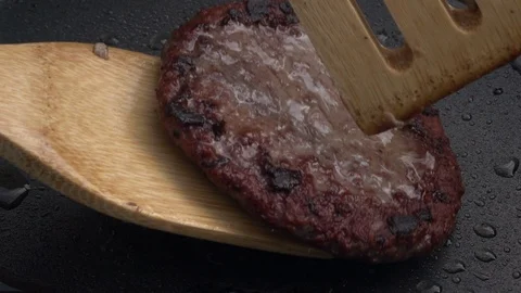 Slow motion of taking freshly roasted hamburger away from dark gray fry pan Stock Footage 99853453