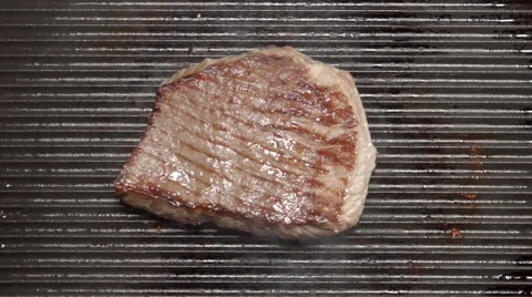 SLOW MOTION: Tasty beef steak fries on a grill (top view) Stock Footage 68489890