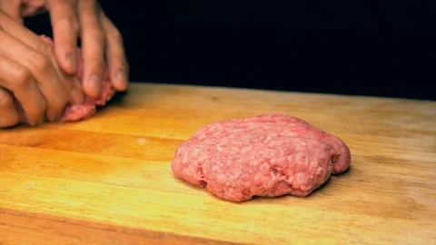 Slow motion tattooed chef hands forming hamburger patties on wood butcher block Stock Footage 94357410