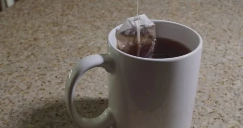 Slow Motion Tea Bag Dipping in White Mug on Granite Counter Stock Footage 321424983