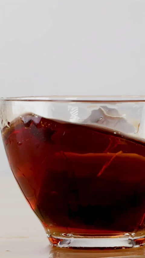 Slow Motion Tea Bag Splash in Glass Cup of Black Tea Stock Footage 342494962