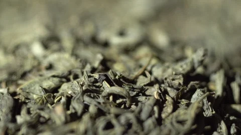 SLOW MOTION: Tea leaves fall on a pile of a green tea - Macro shot. 스톡 동영상 109794574