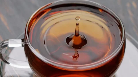 Slow motion tea splash. Droplet falling into golden tea Video stock 237167501