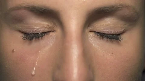 SLOW MOTION: Tear comes out of an eye and streaks down the cheek Video stock 22338426