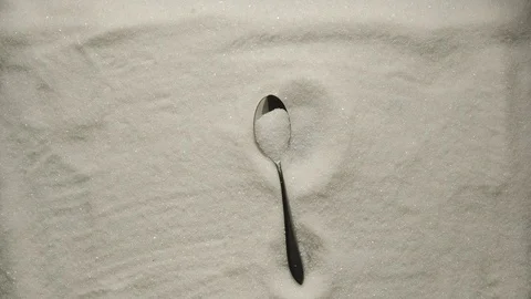 SLOW MOTION: Teaspoon with sugar grains falls onto a heap of white sugar Stock Footage 107932413