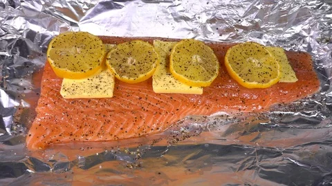 Slow motion then normal speed – Hands wrapping foil over piece of raw salmon. Video stock 105963846