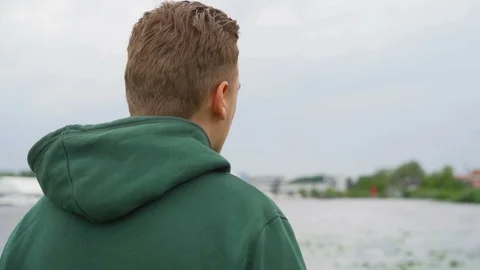 Slow motion of A thoughtful young man who is staring away at the river Stock Footage 91230943