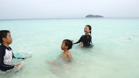 Slow motion of three Asian Thai kids play in a blue ocean  Stock Footage 87897546
