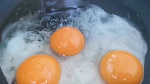 Slow motion of three fresh eggs hitting a hot pan Stock Footage 144415714