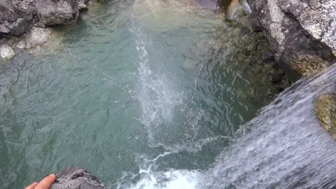 Slow motion: throwing a stone from top of the waterfall Stockbeeldmateriaal 76770242