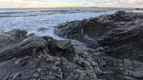 Slow motion tide waves flood between large coastal rock boulders Stock Footage 325721466