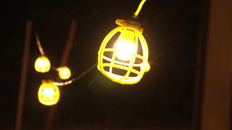 Slow motion tight shot of work light string swinging in snow storm Stock Footage 147334898