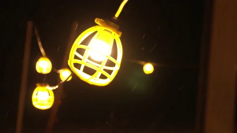Slow motion tight shot of work light string swinging in snow storm Stock Footage 147409648