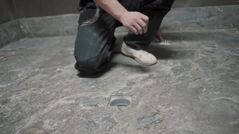 Slow motion tile installation with a man working on a floor drainage system Video stock 307041935
