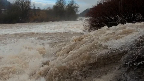 Slow motion tilt down flooding water over concrete canal spillway Stock Footage 120528859