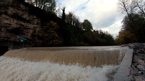 Slow motion tilt down rapid brown river water on man made cascades Video stock 120456554