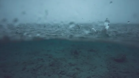 SLOW MOTION: Tiny drops of rain fall into the endless ocean and create a ripple. Stock Footage 90785764