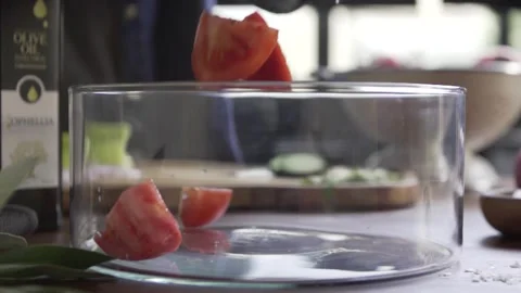 Slow motion of tomato slices dropping on glass bowl Stock Footage 263030266