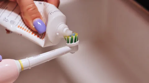 Slow Motion Toothpaste Squeeze on Electric Brush - Close-Up Hygiene Routine Stock Footage 306763346