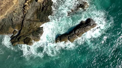 Slow Motion top down drone shot of waves breaking on a rock Stock Footage 345424303