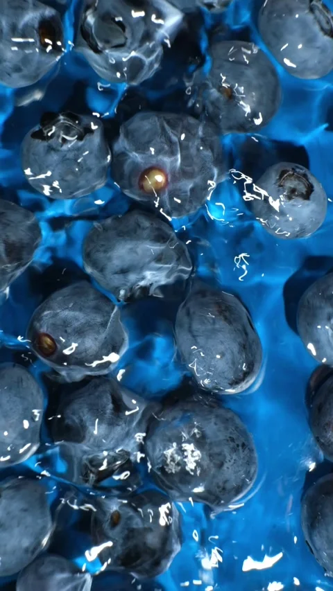 Slow motion top view of blueberries in splashing blue water. Stock Footage 338397039