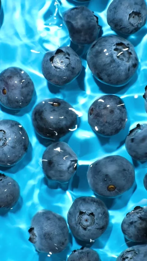 Slow motion top view of blueberries in splashing blue water. Stock Footage 340550182