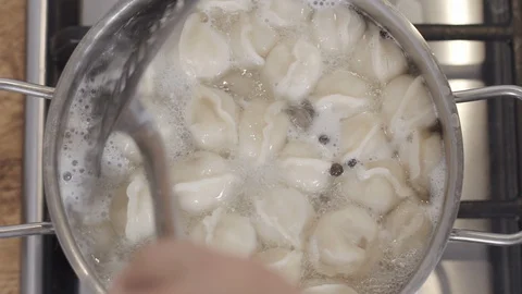 Slow motion top view footage of cooking dumplings in boiling water in pan. Male Stock-Footage 128300636