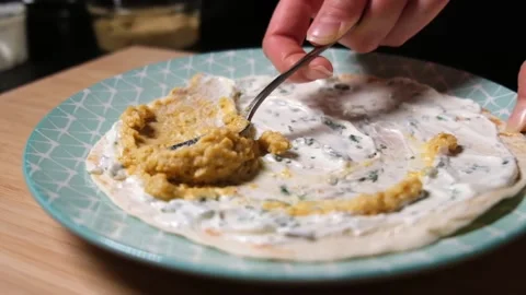 Slow motion tracing shot of spreading hummus on a wrap. Stock Footage 154713179