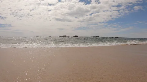 Slow motion tracking shot along shoreline of sandy beach 動画素材 132936775