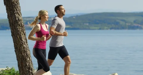 Slow Motion Tracking Shot Of Man And Woman Jogging Stock Footage 123850520
