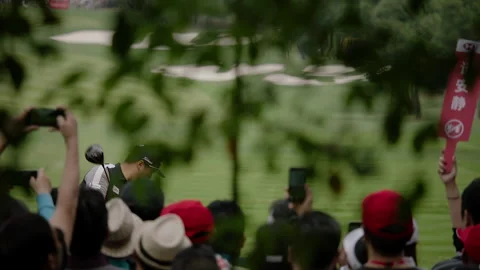 Slow motion tracking shot of pro golfer tee shot with fans Stock Footage 143000872