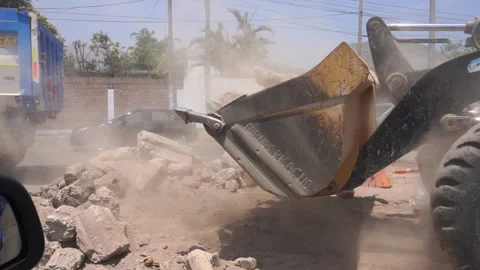 Slow motion of a tractor picking up debris and stones on the road Stock Footage 150917808
