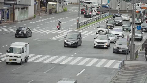 Slow motion traffic moving through large intersection near Hakata Station Japan Stock Footage 327722434