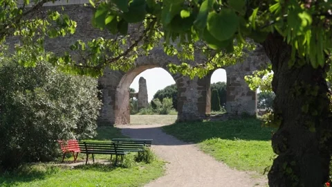Slow motion of a tree and bench in a park near an ancient aqueduct Stock Footage 328033731