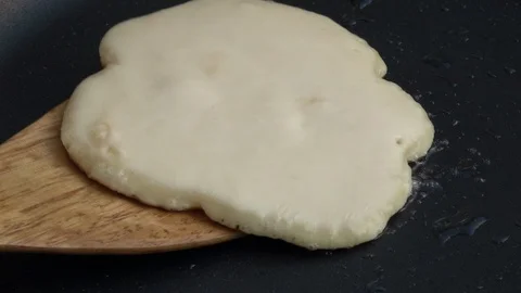 Slow motion of turning batter cake on hot dark gray fry pan close up. Stock Footage 100235826