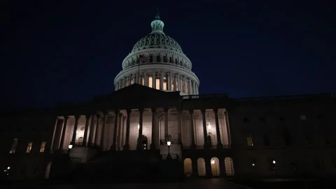 Slow motion turning view of the East side of the US Capitol dome with flags Stock Footage 239333009
