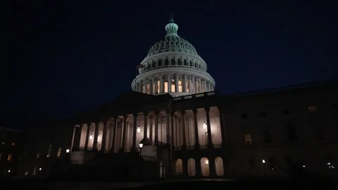 Slow motion turning view of the US Capitol dome with flags waving in Washington Stock Footage 238353019
