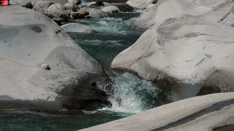 Slow motion of turquoise mountain stream flowing between two large pale boulders Stockbeeldmateriaal 346247180